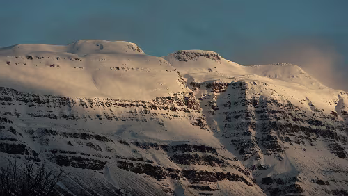 Seyðisfjörður Die verschneiten Berge um Seyðisfjörður werden von den ersten Sonnenstrahlen erwacht.